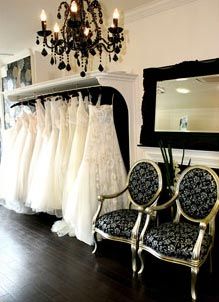 a room filled with lots of white dresses and a chandelier hanging from the ceiling