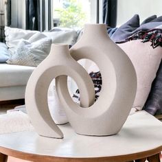 a white vase sitting on top of a table next to a couch in a living room