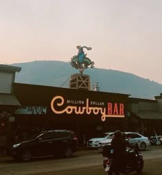 a motorcycle parked in front of a building with a neon sign on it's roof