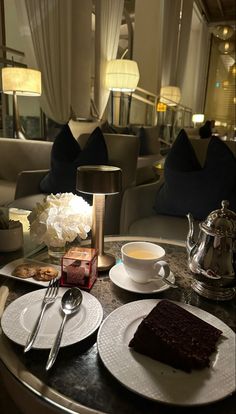 a table topped with plates and cups filled with desserts next to a vase full of flowers