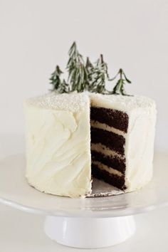 a cake with white frosting and green sprigs on top is cut in half