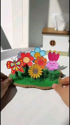 someone is cutting out some flowers on a piece of paper that looks like a house