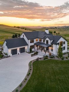 an aerial view of a large white house in the middle of a green field at sunset