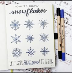 an open notebook with snowflakes drawn on it next to two markers and pens