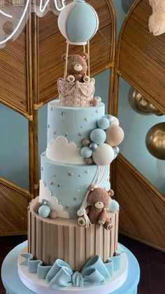 a three tiered cake with teddy bears and balloons on it's top layer