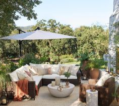 an outdoor living area with couches, tables and umbrellas