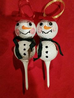 two snowman golf balls on top of each other with a gold ribbon around their necks