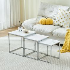 two tables sitting on top of a white rug in front of a living room couch