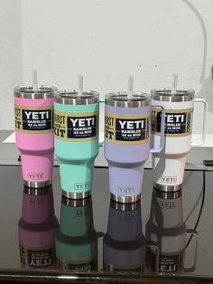 four yeti travel mugs sitting on top of a glass table next to each other