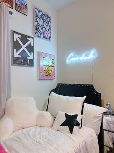 a white bed sitting under a neon sign in a bedroom