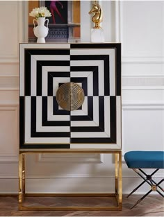 a black, white and gold cabinet with an abstract design on the front in a living room