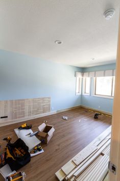 an empty room with blue walls and hard wood flooring in the foreground is being remodeled