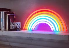 a rainbow light sitting on top of a book shelf next to a pile of books