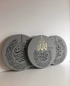 three plates with arabic calligraphy on them are lined up against a white wall,