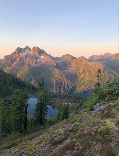 the mountains are covered in snow and green grass as the sun is setting on them