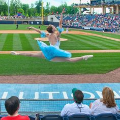 a ballerina is performing on the field at a baseball game