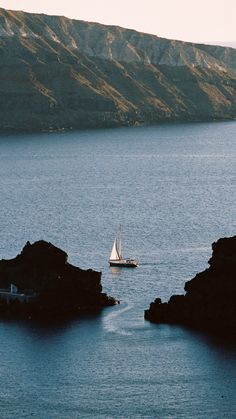 a sailboat is out on the water near some rocks