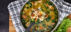 a pot filled with soup and vegetables on top of a wooden table