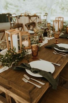 the table is set with plates, candles and greenery for an outdoor wedding reception