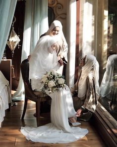 two women dressed in muslim garb sit on a chair and look at each other