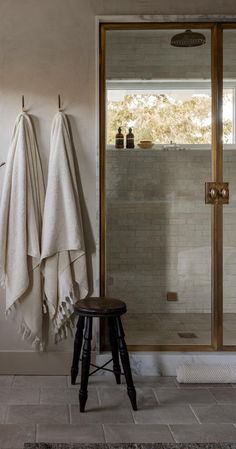 a white towel is hanging on the wall next to a stool and shower in a bathroom