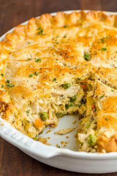 a casserole with chicken and vegetables is cut in half on a wooden table