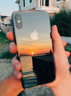 someone is holding up their iphone to take a photo with the sunset in the background