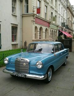 an old blue car is parked on the street