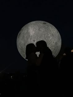 two people are kissing in front of the moon