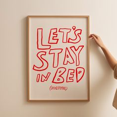 a person holding up a poster with the words let's stay in bed