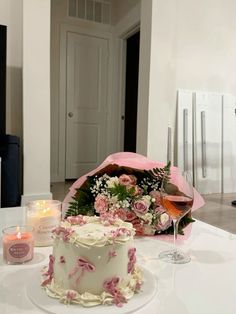 a white table topped with a cake next to a glass of wine and candlelight