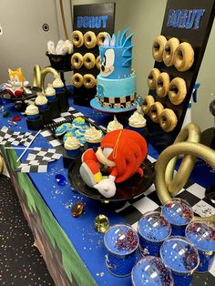 a table topped with lots of donuts and desserts on top of blue cloth covered tables