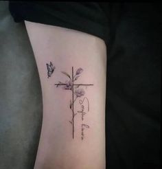 a cross with flowers and a butterfly tattoo on the side of her leg that says, i love you