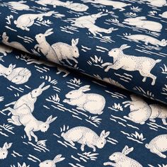 the fabric is blue with white rabbits and grass on it, as well as an image of