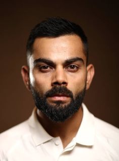 a man with a goatee and beard wearing a white shirt looking at the camera