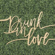 the words drunk love are placed on top of a green wall covered in ivy leaves