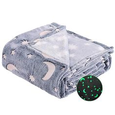 a blanket that has stars and moon on it with a green glow in the middle