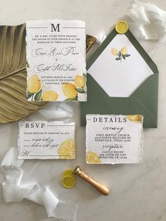 the wedding stationery is laid out on a marble table with gold and green accents