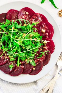 beet salad on a white plate with silverware