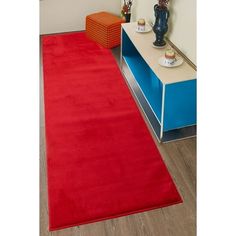 a red rug is on the floor next to a blue cabinet