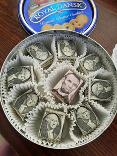 some money is sitting in a bowl on a table next to a box of royal danish cookies