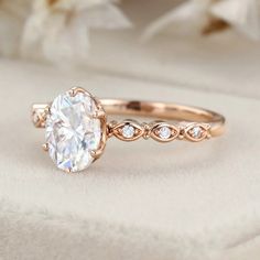 a close up view of a diamond ring on a white cloth with flowers in the background