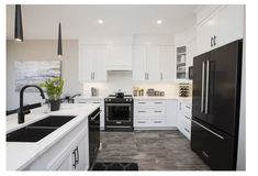 a black and white kitchen with stainless steel appliances, marble counter tops, and tile flooring