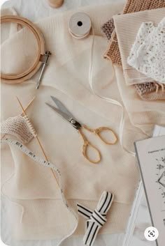 sewing supplies laid out on top of a white cloth with scissors, thread and other items