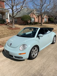 a light blue convertible car parked on the side of a road in front of a house