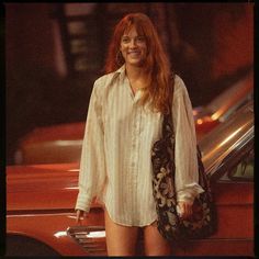 a woman standing in front of a red car