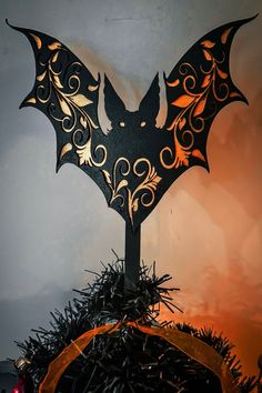 a bat shaped metal decoration sitting on top of a table next to a christmas tree