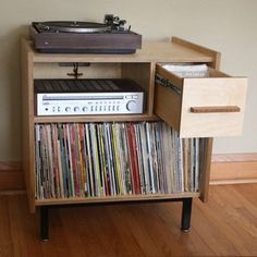 an old record player sits on top of a wooden cabinet with records and cassettes