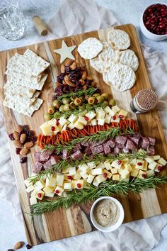 a wooden cutting board topped with cheese and crackers next to other food on top of a table