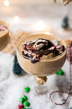 two glasses filled with ice cream and candy canes on top of snow covered ground